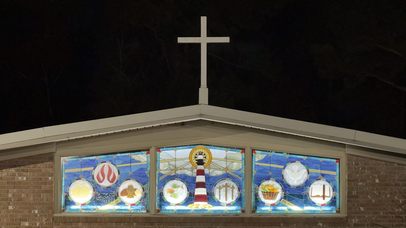 The lighthouse stained glass window at Harbor View Presbyterian, lit from inside at night